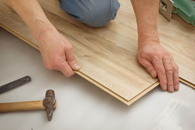 Man Makes Laying Laminated Panels — Flooring Direct Mid North Coast in South Kempsey, NSW