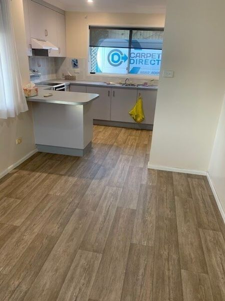 A Kitchen With A Wooden Floor And White Cabinets — Flooring Direct Mid North Coast in South Kempsey, NSW