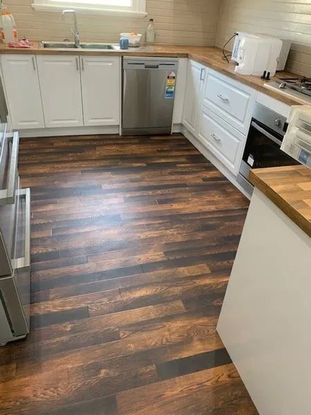 A Kitchen With A Wooden Floor And White Cabinets — Flooring Direct Mid North Coast in South Kempsey, NSW
