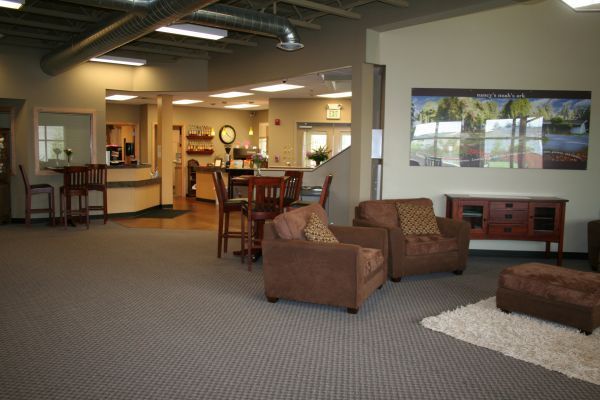 Spacious lobby with seating area, carpet, tables, and a wall-mounted landscape display