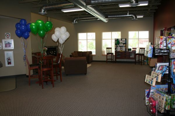 Library lounge with balloons, chairs, bookshelves, and large windows.
