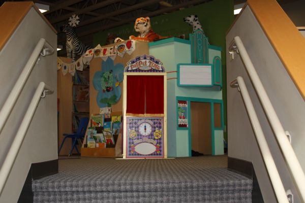 Small colorful theater or playhouse facade at the top of stairs in an indoor setting