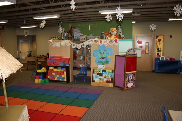 Empty daycare playroom with colorful mats, toys, and wall decorations