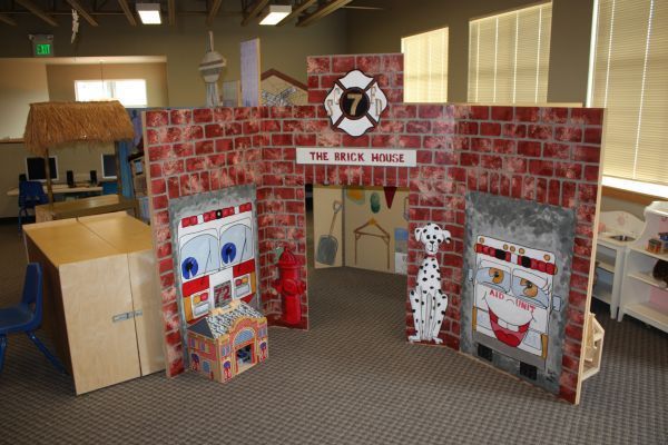 Cardboard fireplace display with red brick pattern and school-style posters in an indoor lobby