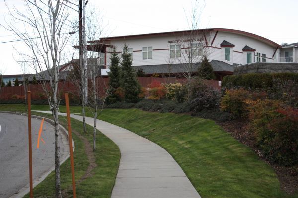 Curved sidewalk beside landscaped lawn leading to a large white building on a hillside