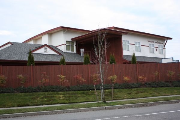 Modern two-story house with red fence and front lawn beside a street