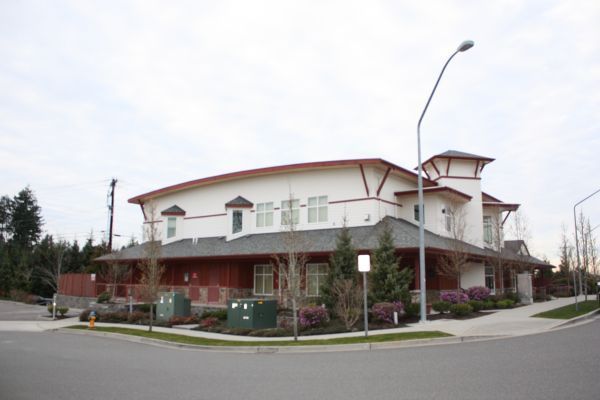 Corner building with red trim and white walls on a street corner, viewed from across the road.