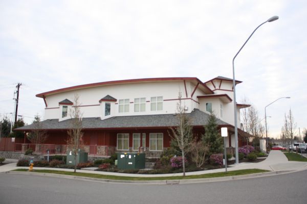 Two-story corner building with red trim, windows, and a covered walkway on a cloudy day