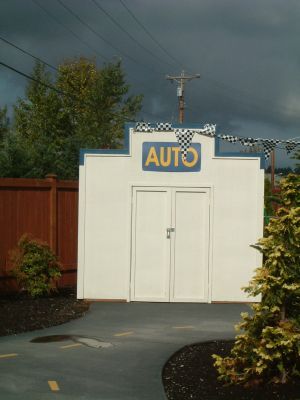 White building with blue trim and an “AUTO” sign above double doors, beside a curved walkway.