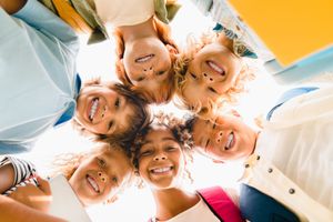 Smiling group of people lying in a circle and looking down at the camera outdoors