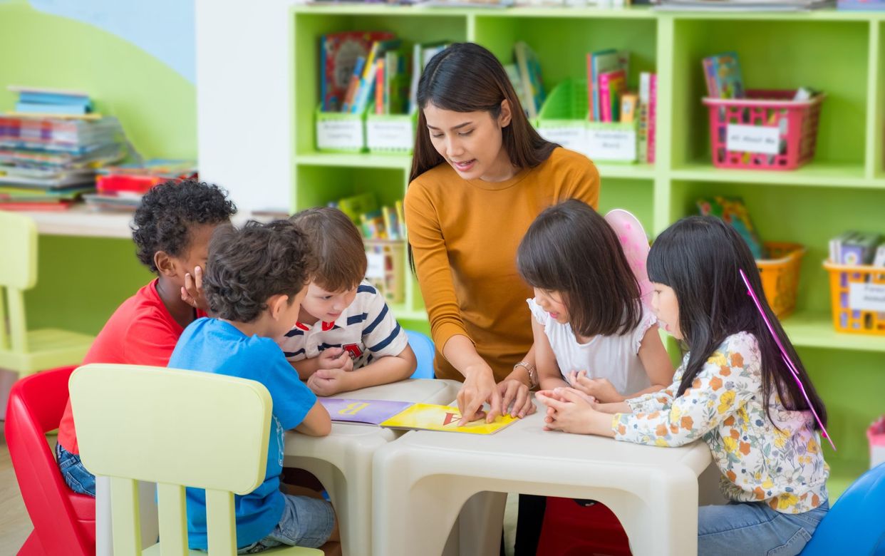 Children sitting on a classroom carpet and clapping during a group activity