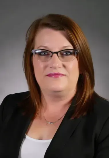 Woman in glasses and blazer, headshot.