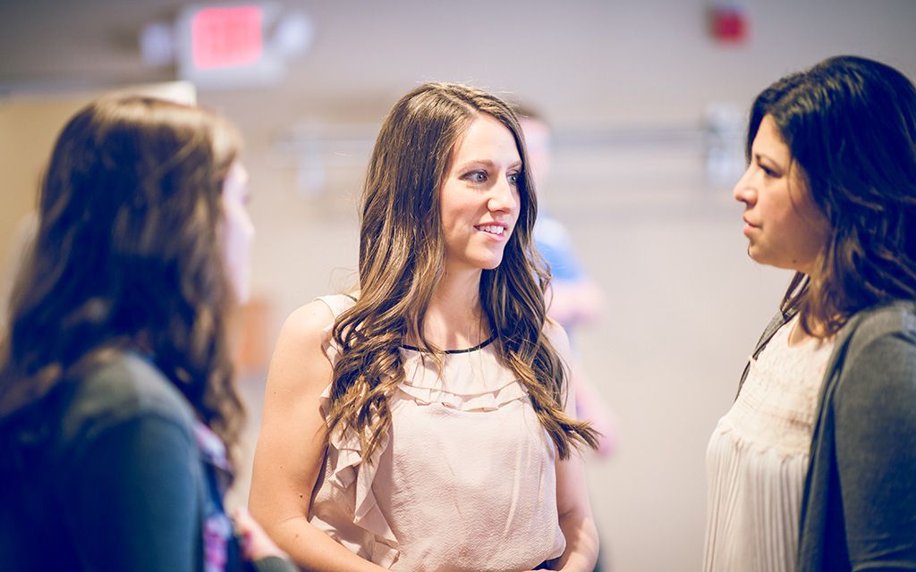 a woman in a pink top is talking to two other women