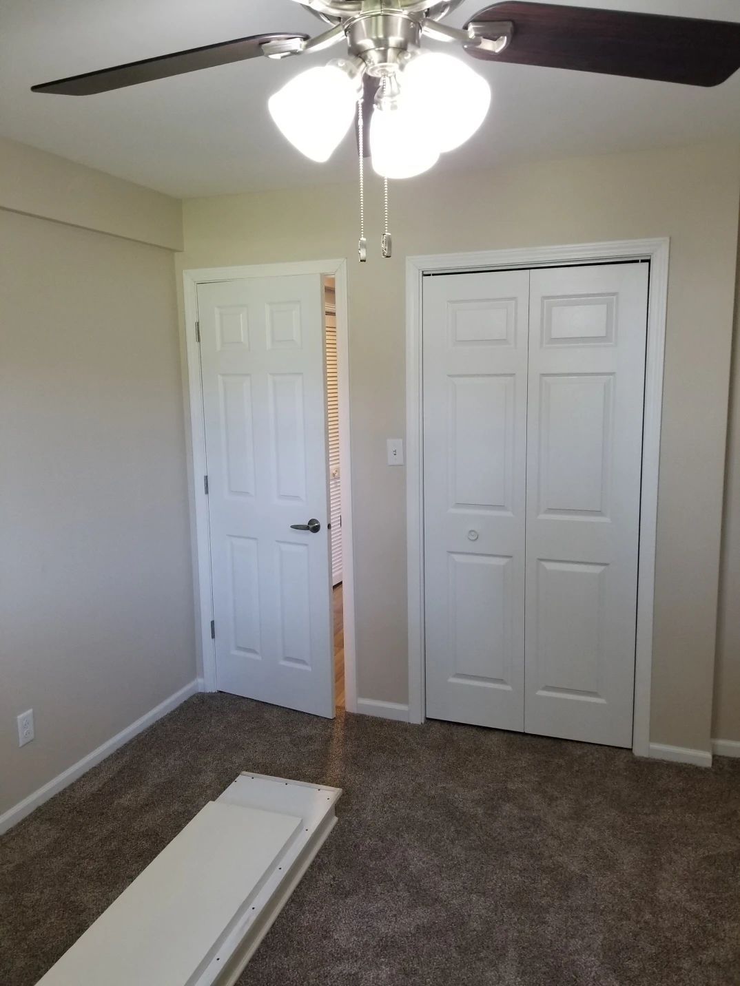 Bedroom with white doors, closet, ceiling fan, and carpet.