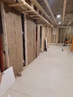 Basement under construction, framed walls with insulation and concrete floor.