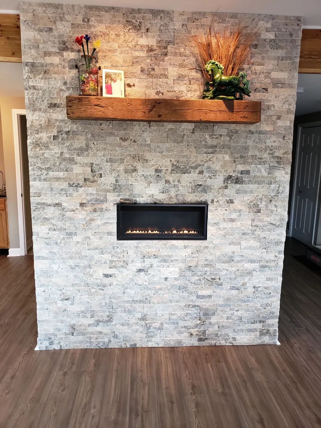 Stone-tiled fireplace with a wooden mantle, an electric fireplace, and decorative items.