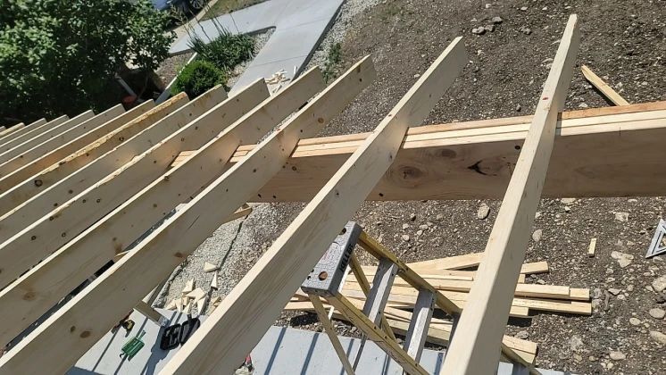 Wooden roof rafters being constructed on a rooftop, viewed from above.