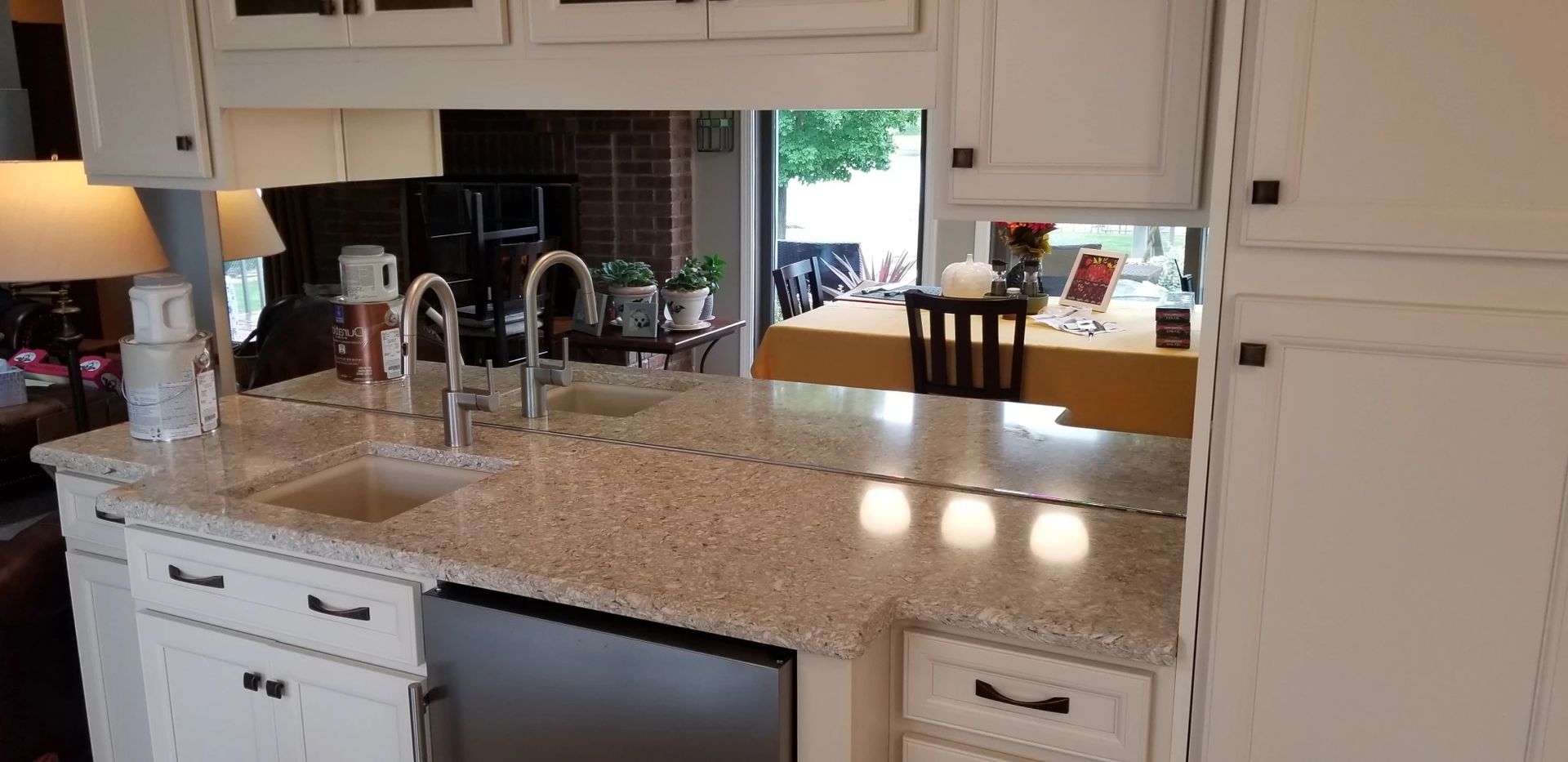 Kitchen interior with white cabinets, speckled countertop, and sink. Dining area visible in the background.