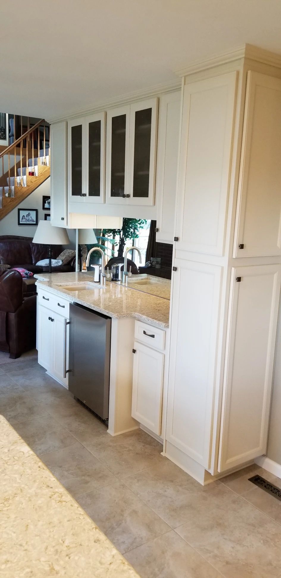 White kitchen with granite countertops, stainless steel dishwasher, and cabinet storage.