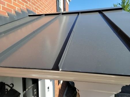 Black metal awning over a white trim doorway, attached to a brick wall.