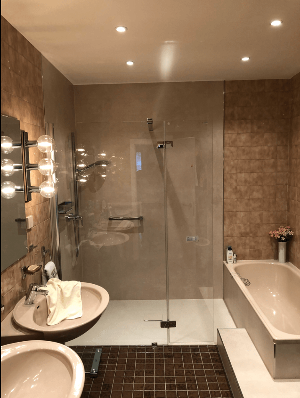 Ein Badezimmer mit zwei Waschbecken, einer Badewanne und einer ebenerdigen Dusche.