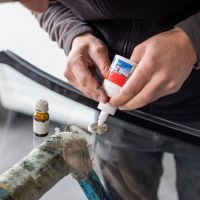 A person is applying glue to a broken windshield.