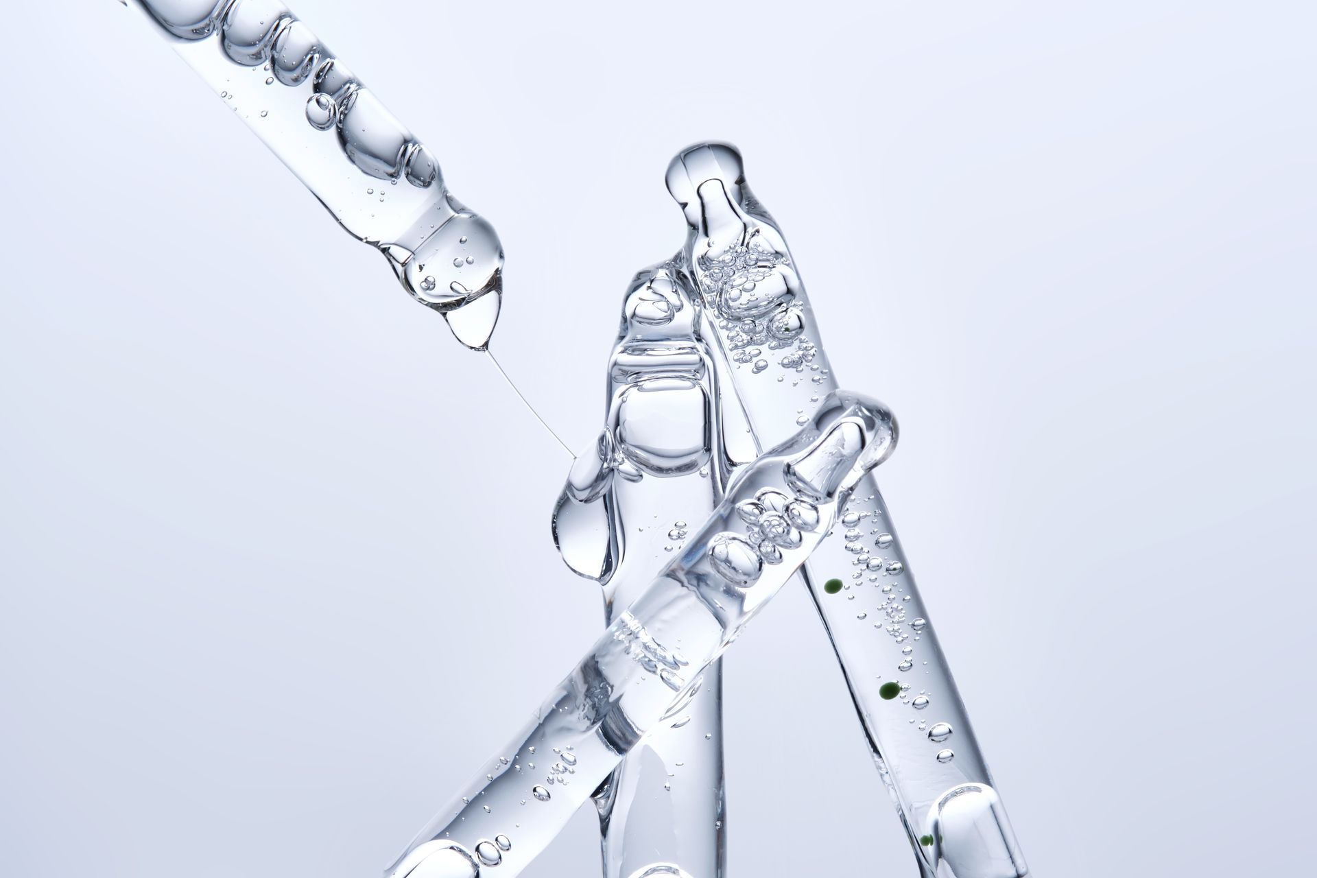 Transparent pipettes and glass droppers with water droplets on a light background