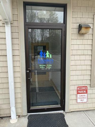 Glass entry door with accessibility decal and red reserved parking sign beside it