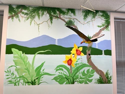 Mural of mountains, lake, and flowers with a hummingbird in a classroom setting
