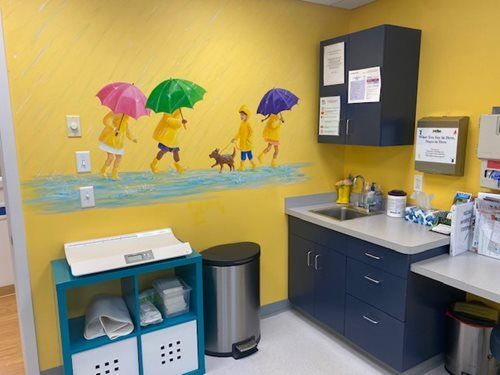 Dental office sink area with yellow mural of children holding colorful umbrellas