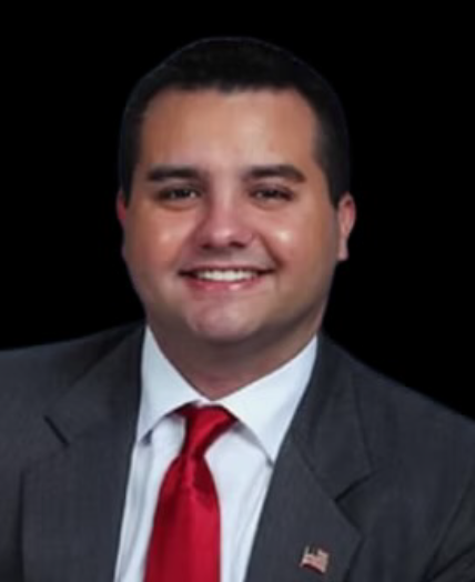 Smiling man in a gray suit and red tie against a black background