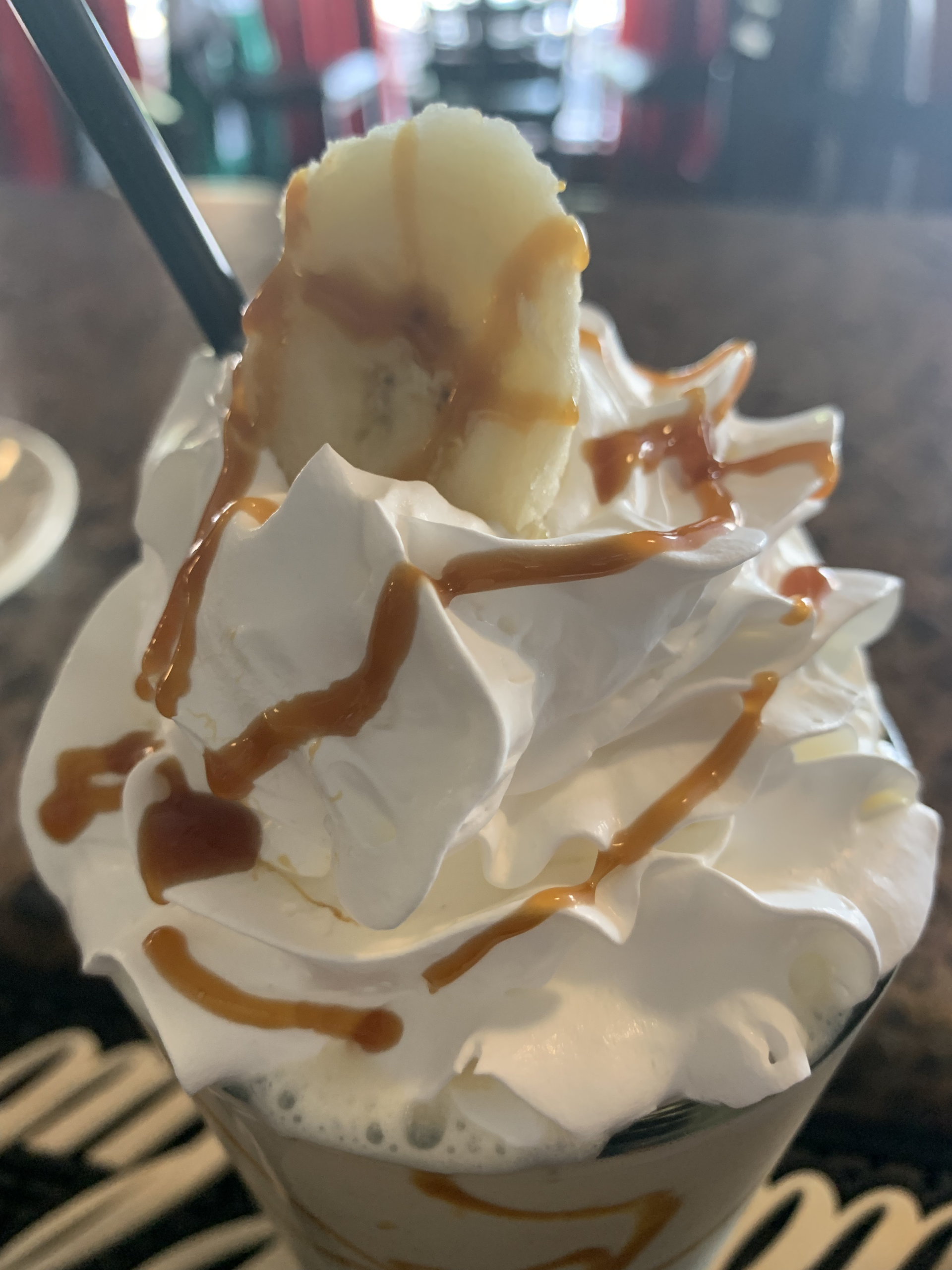 A banana milkshake with whipped cream and caramel sauce