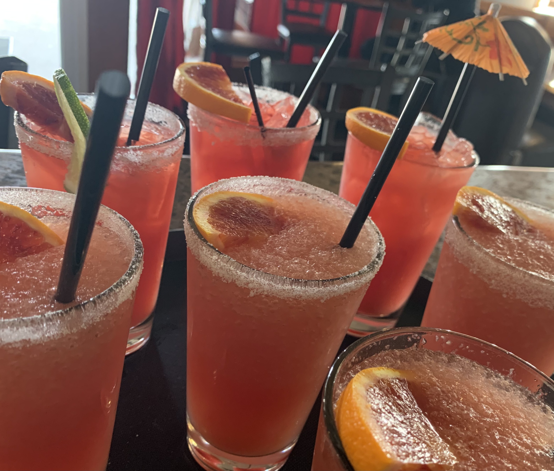 A bunch of pink drinks with straws on a table