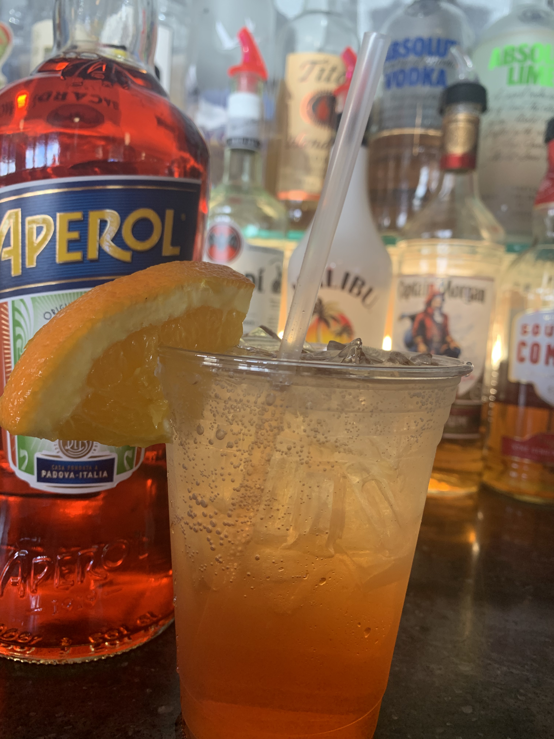 A bottle of aperol next to a cup of drink