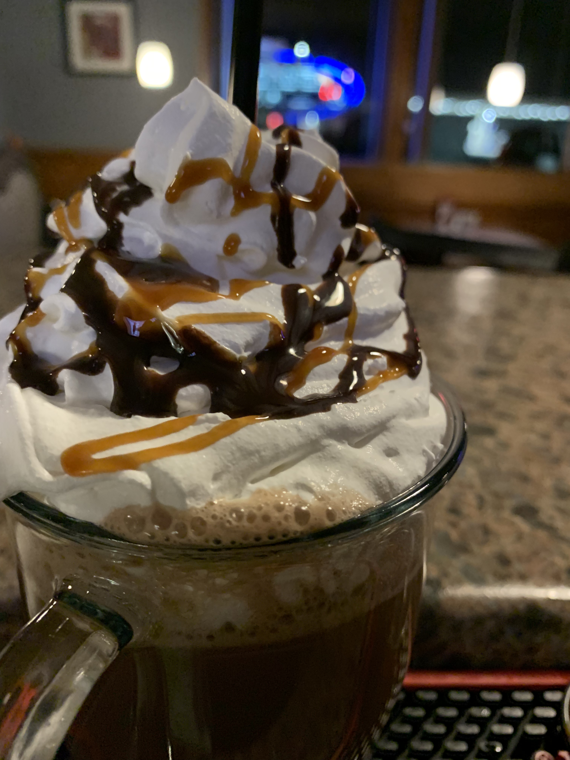 A close up of a chocolate drink with whipped cream and caramel sauce