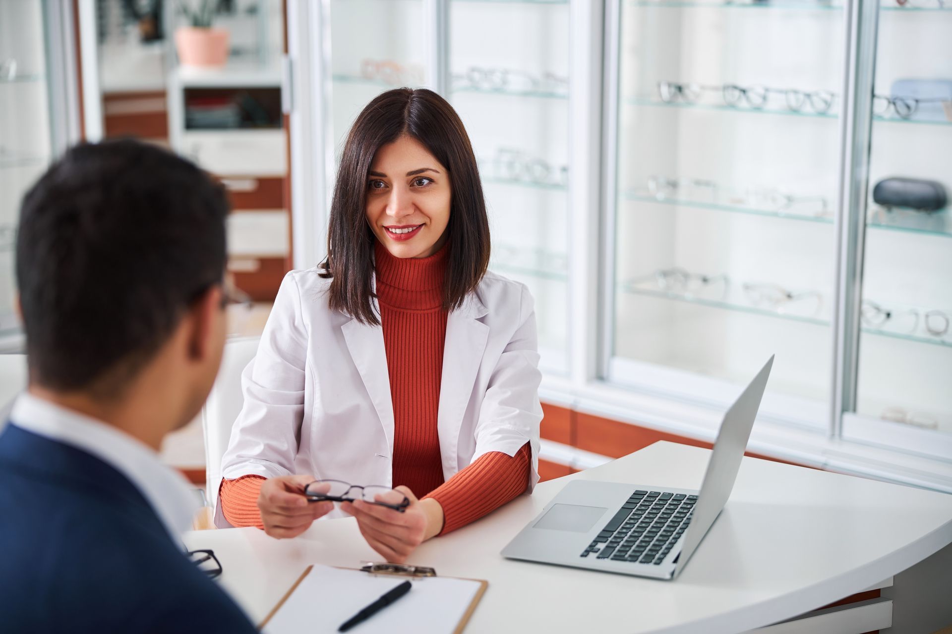 A female optometrist is showing the eyewear to her client. A female optometrist is showing the eyewear to her client.