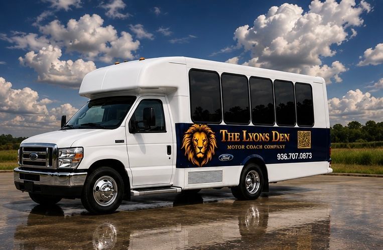 White passenger shuttle van with lion logo and “The Lyons Den” parked on wet pavement under a cloudy sky