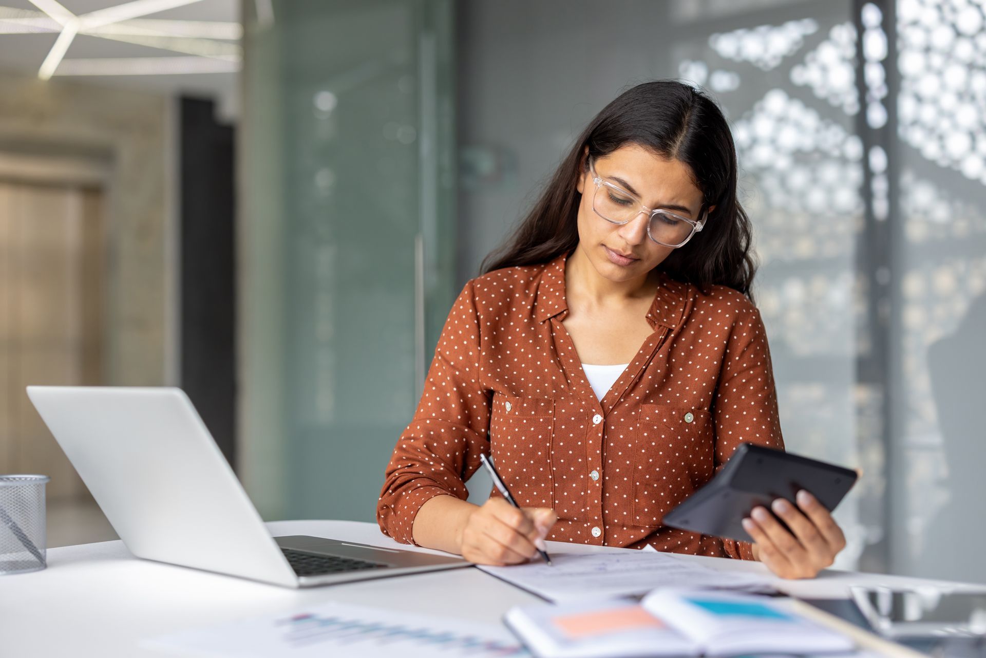 Young businesswoman calculating finances on a calculator. Young businesswoman calculating finances on a calculator.