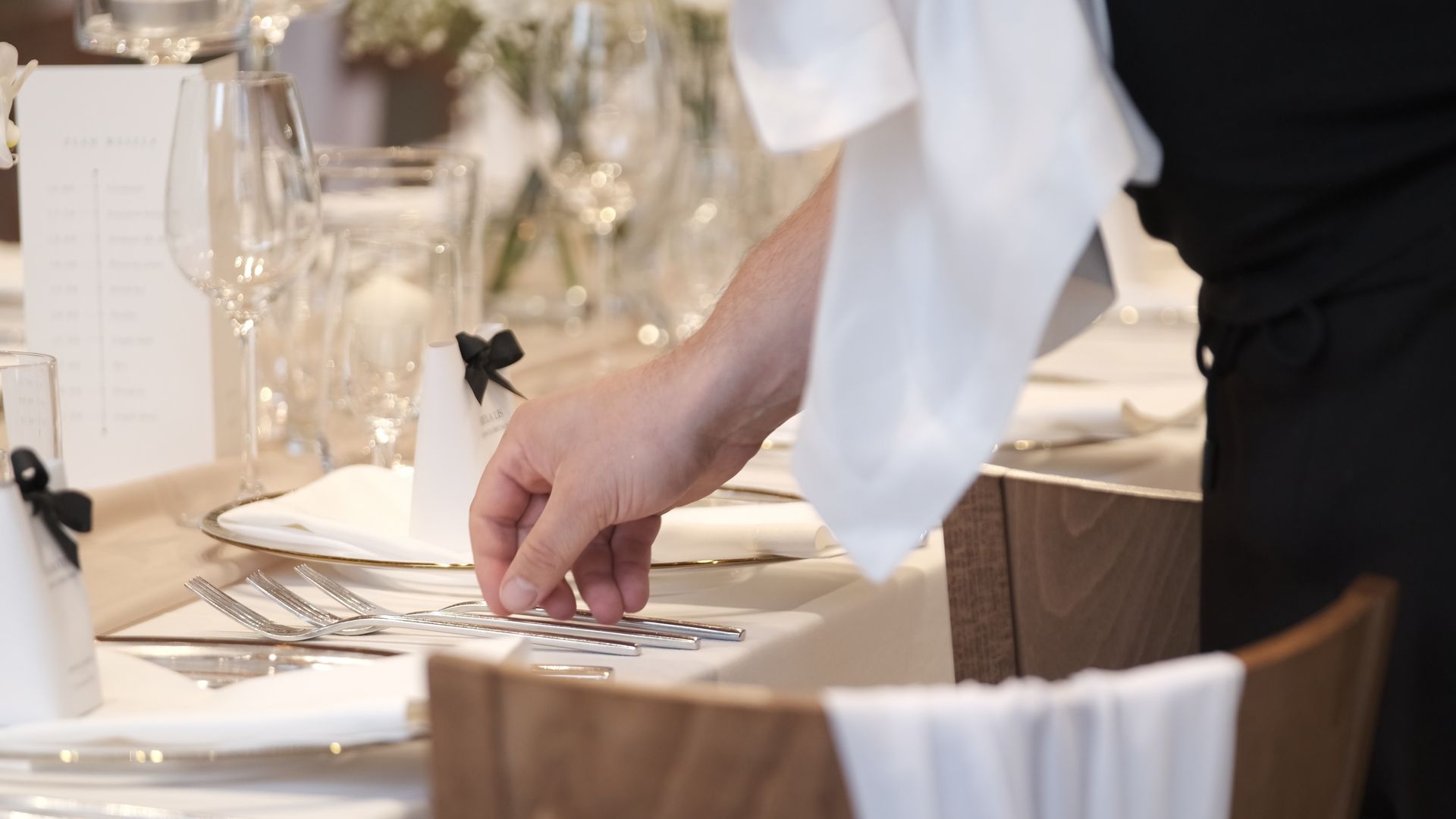 Server arranging silverware on an elegant restaurant table