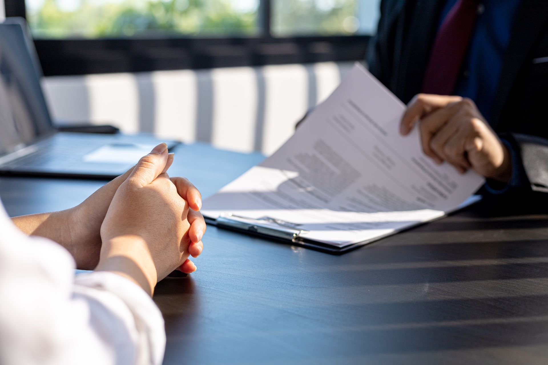 Hands signing a document across a table in a bright office meeting room