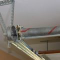 Garage door torsion spring, coiled, with red marking. Mounted on brackets.