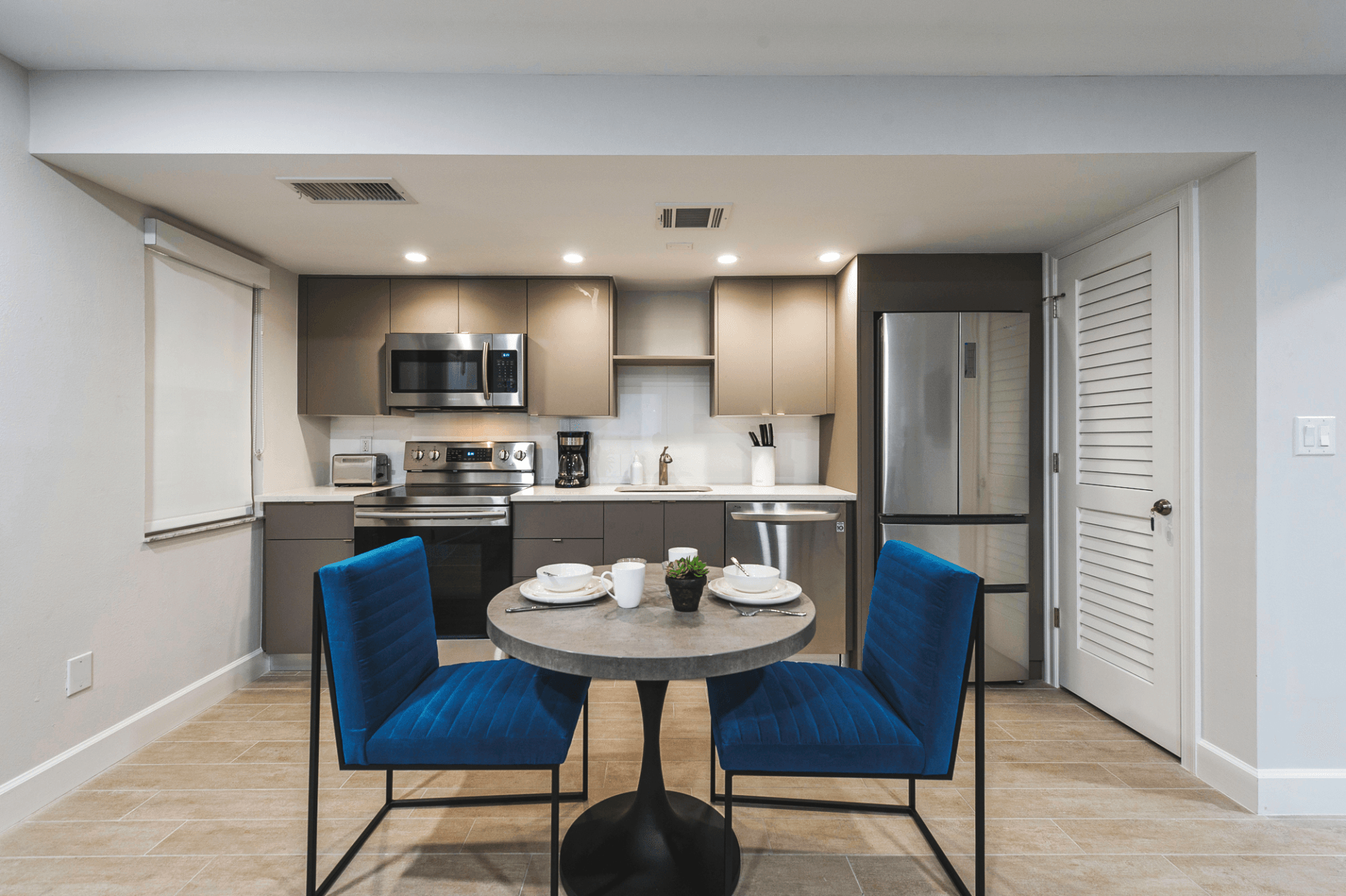 Modern kitchen and dining area with blue chairs, round table, and stainless steel appliances