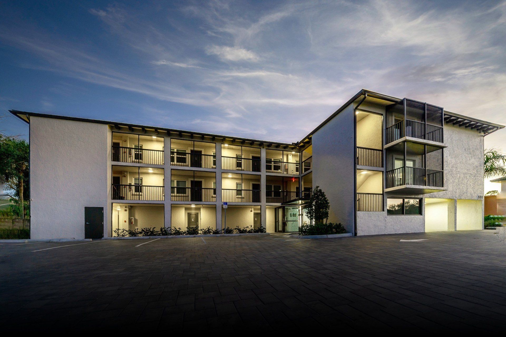 Modern two-story building with lit balconies at dusk