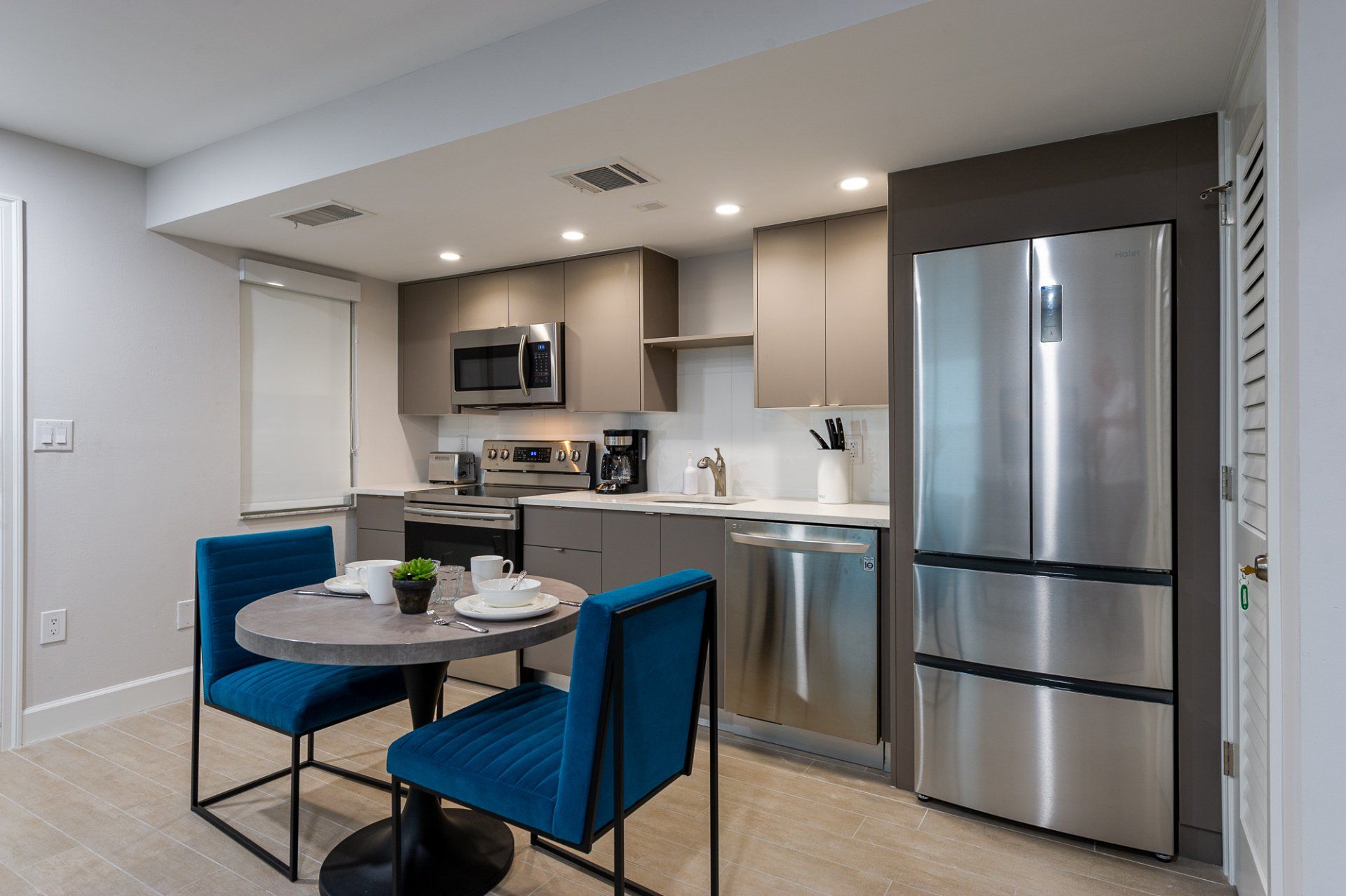 Modern kitchen with stainless appliances and a small dining table with blue chairs
