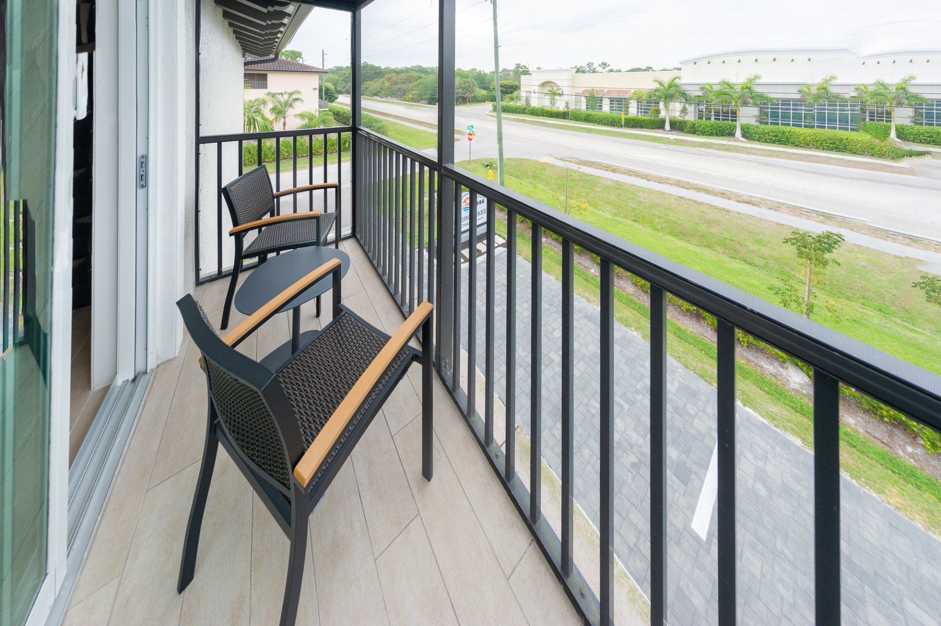Balcony with two black chairs overlooking a road and green landscape