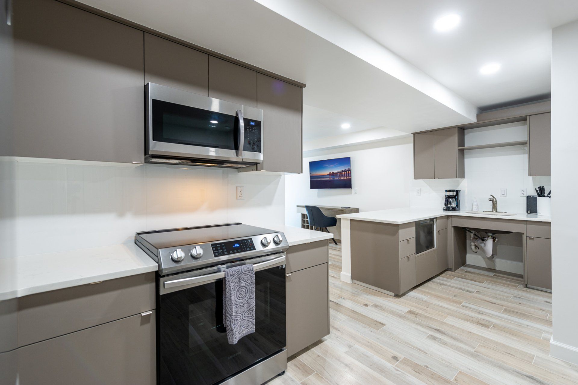 Modern kitchen with stainless steel stove, microwave, gray cabinets, and light wood flooring
