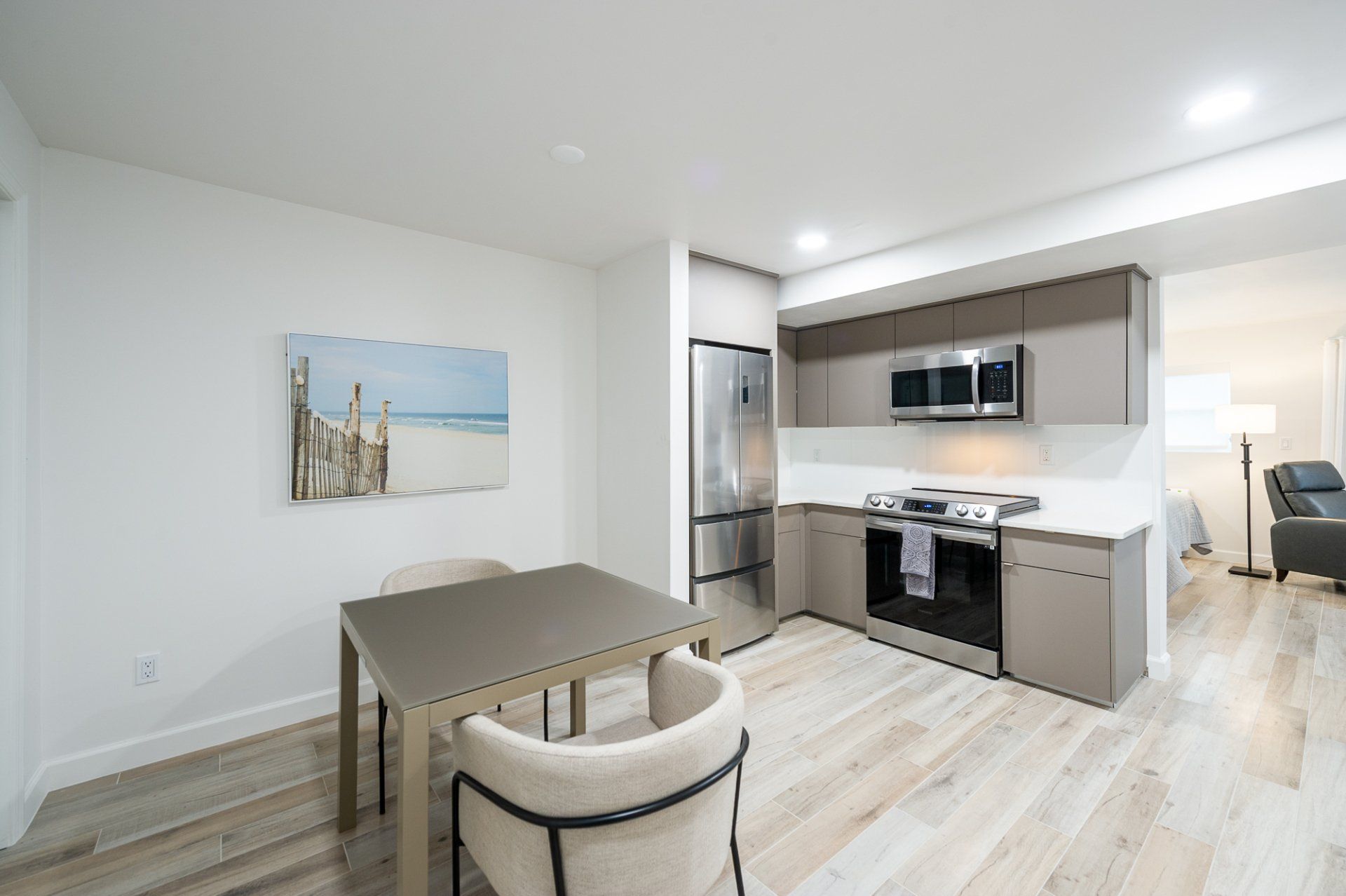Bright kitchen and dining area with stainless appliances, gray cabinets, and a small table by the window.