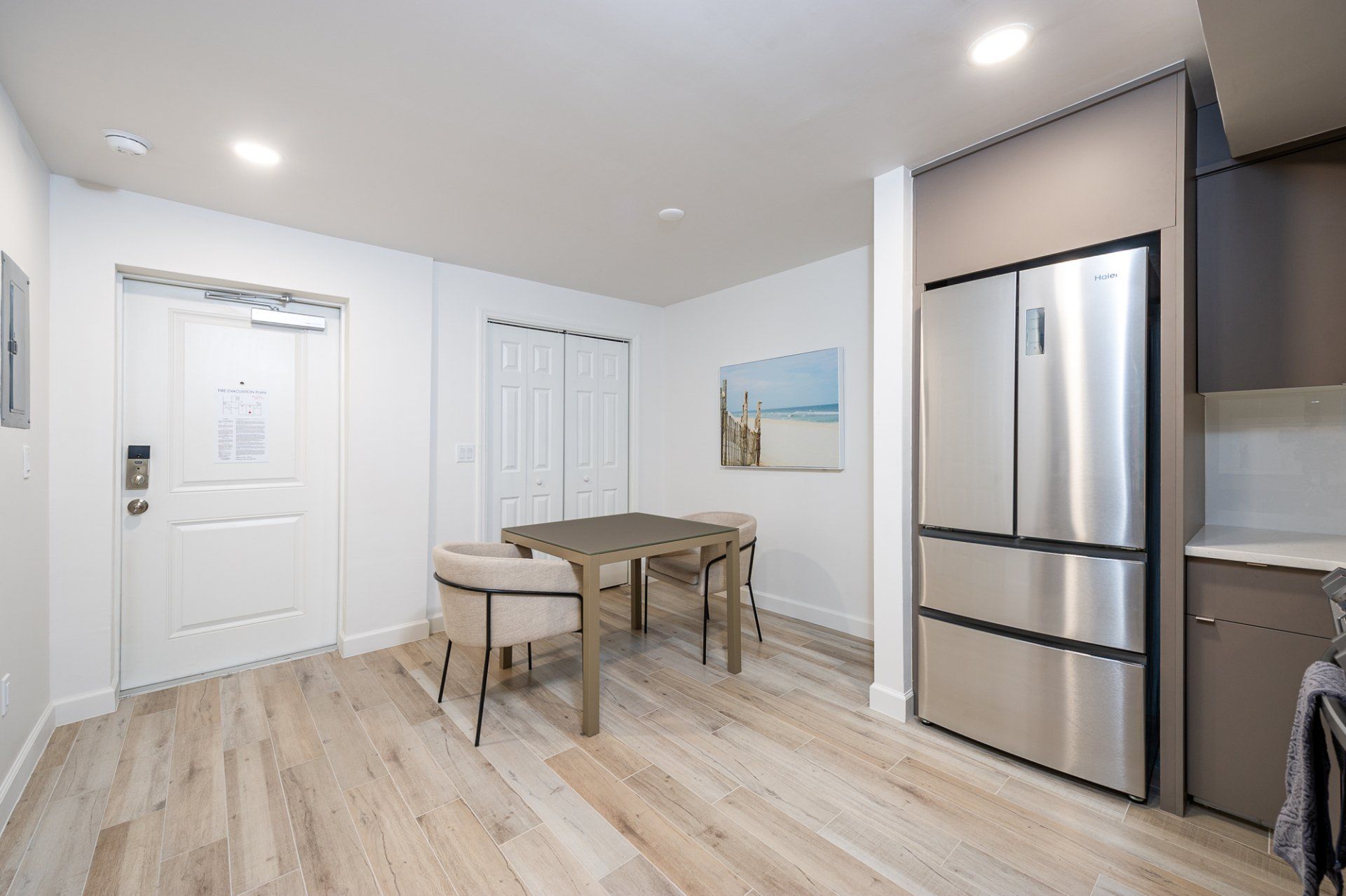 Bright kitchen nook with table, bench, white walls, and stainless steel refrigerator
