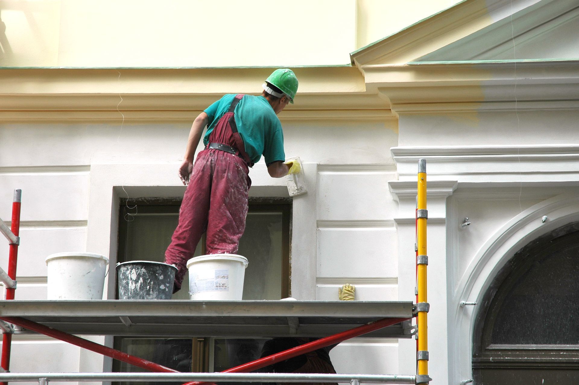 A man is painting the exterior of a house. A man is painting the exterior of a house.