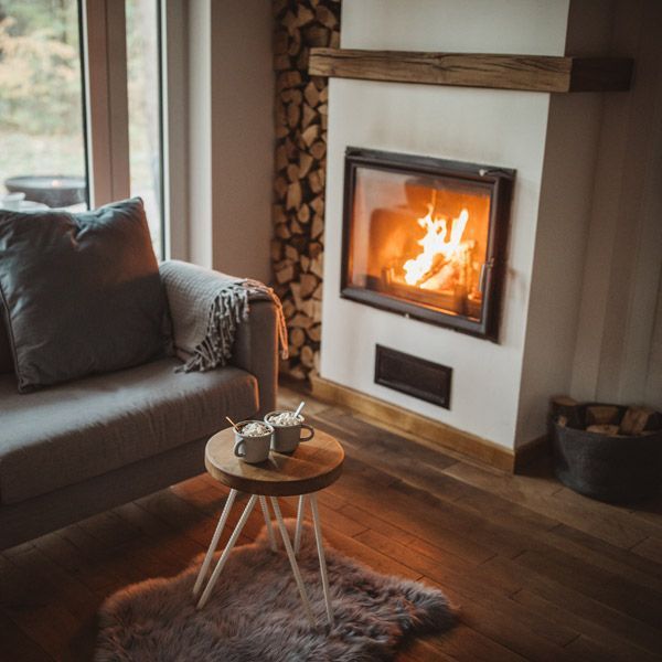 Cozy living room with a lit fireplace, gray sofa, and small wooden coffee table on a fur rug